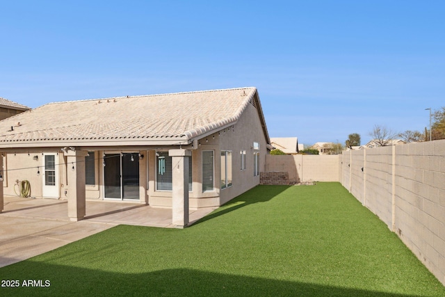 rear view of property featuring a lawn and a patio area