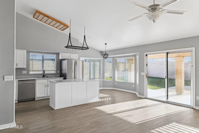 kitchen with hardwood / wood-style flooring, appliances with stainless steel finishes, white cabinetry, a center island, and decorative light fixtures