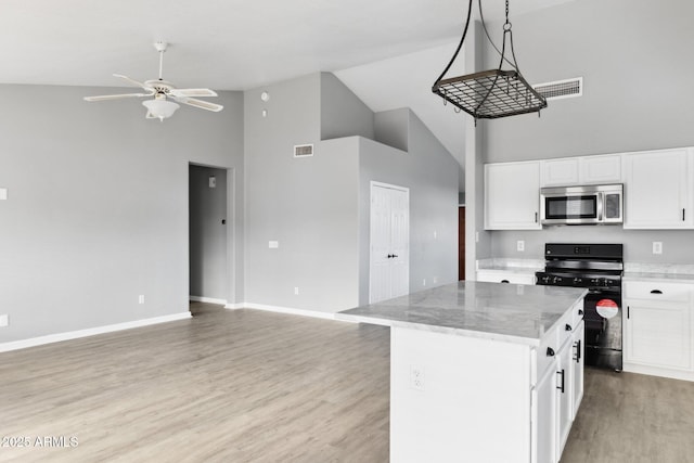 kitchen featuring white cabinetry, a center island, black gas range oven, and decorative light fixtures