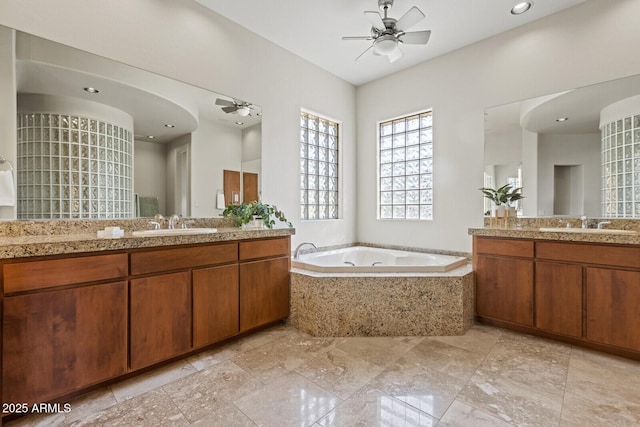 bathroom featuring a sink, two vanities, a bath, and ceiling fan