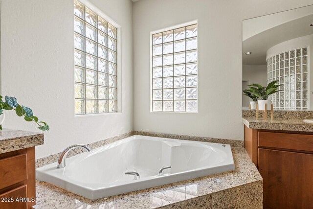 full bathroom featuring a garden tub and vanity