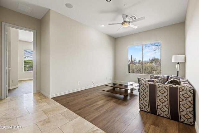 living area with visible vents, baseboards, wood finished floors, and a ceiling fan
