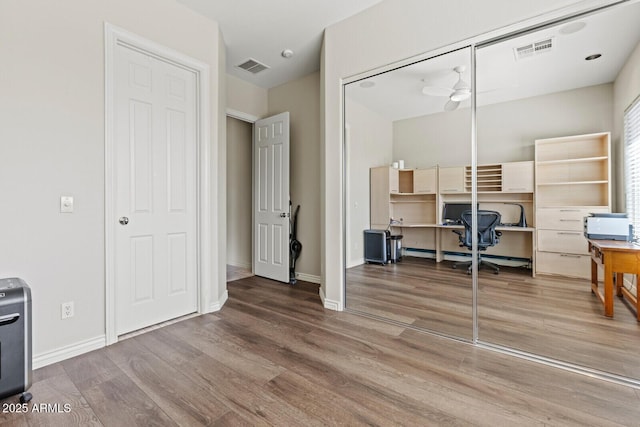 office space featuring ceiling fan, visible vents, baseboards, and wood finished floors