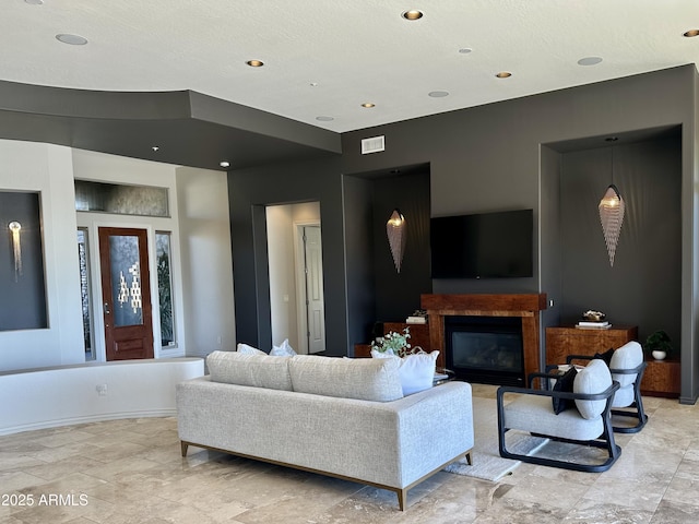 living room with a glass covered fireplace, recessed lighting, baseboards, and visible vents