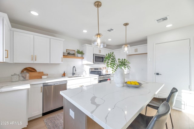 kitchen featuring open shelves, a kitchen island, appliances with stainless steel finishes, and white cabinets