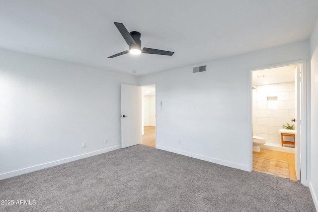 unfurnished bedroom with ceiling fan, connected bathroom, carpet flooring, visible vents, and baseboards