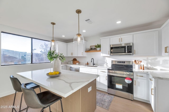 kitchen with appliances with stainless steel finishes, pendant lighting, white cabinetry, open shelves, and a sink