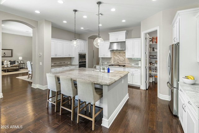 2051 E Aris Dr, Gilbert, AZ 85298 - kitchen featuring an island with sink, under cabinet range hood, backsplash, arched walkways, and appliances with stainless steel finishes