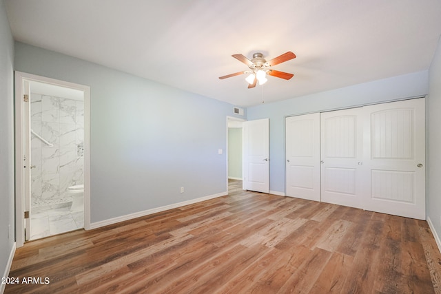 unfurnished bedroom with ceiling fan, a closet, ensuite bathroom, and hardwood / wood-style flooring