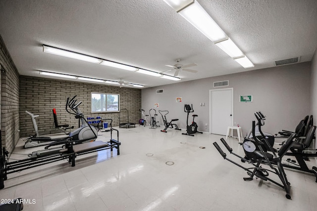 gym featuring a textured ceiling, brick wall, and ceiling fan