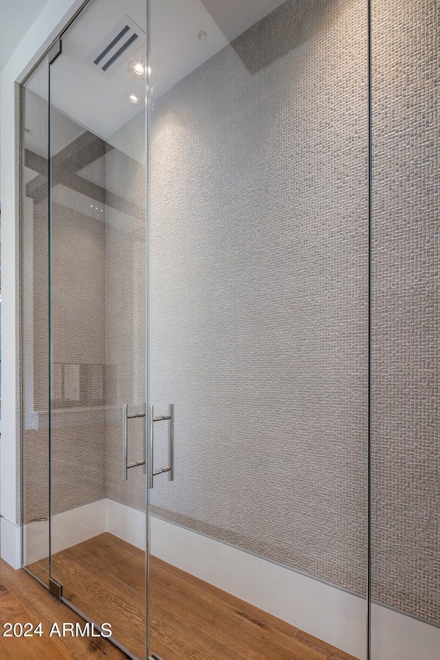 bathroom featuring wood-type flooring and a shower with shower door