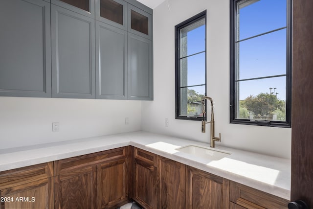 kitchen with glass insert cabinets, light countertops, and a sink