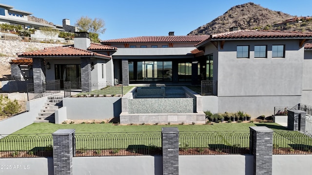 back of property with a mountain view and a lawn