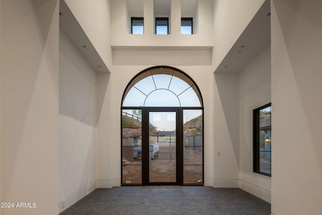 foyer entrance featuring dark parquet flooring and a high ceiling