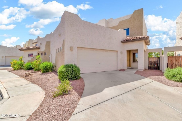 view of home's exterior featuring a garage, fence, stucco siding, a tiled roof, and driveway