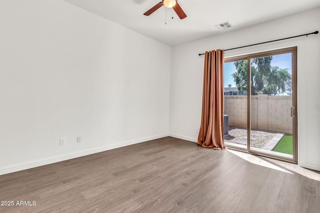 empty room with baseboards, ceiling fan, wood finished floors, and visible vents