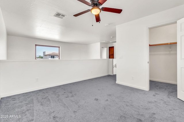 unfurnished bedroom with visible vents, a ceiling fan, baseboards, a walk in closet, and carpet flooring