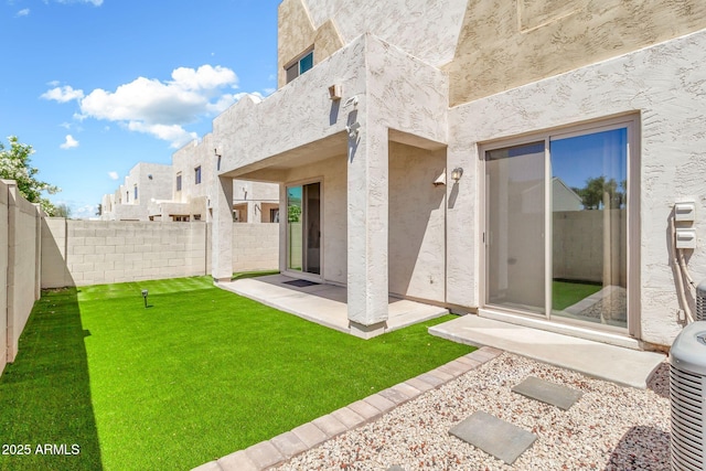back of property with a yard, a fenced backyard, a patio area, and stucco siding
