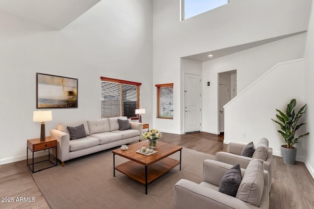 living room featuring baseboards, a high ceiling, and wood finished floors