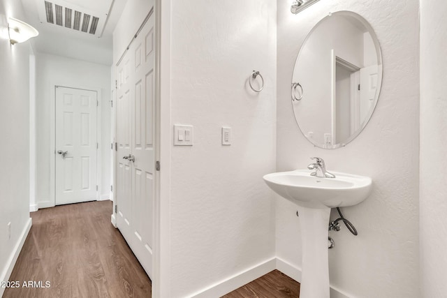 bathroom with visible vents, a sink, baseboards, and wood finished floors