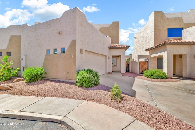 view of front of house featuring fence, an attached garage, stucco siding, a tiled roof, and driveway
