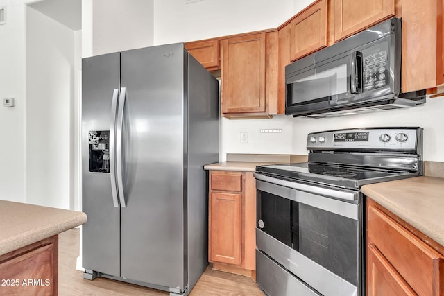 kitchen featuring light wood-type flooring, light countertops, appliances with stainless steel finishes, and brown cabinets