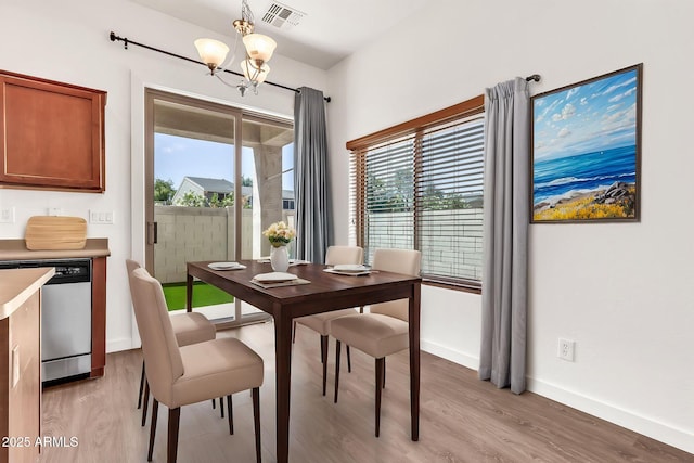dining area featuring a chandelier, visible vents, plenty of natural light, and light wood-type flooring