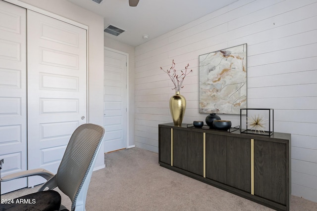 carpeted office space featuring ceiling fan and wood walls