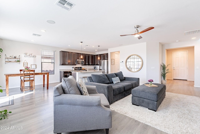 living room with ceiling fan and light hardwood / wood-style flooring