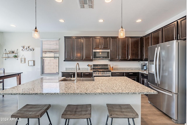 kitchen with dark brown cabinetry, pendant lighting, stainless steel appliances, and sink