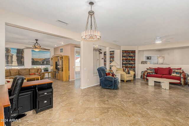 living area with baseboards, visible vents, and a ceiling fan