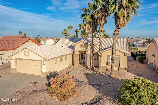 mediterranean / spanish-style home featuring a garage, a tile roof, concrete driveway, a residential view, and stucco siding