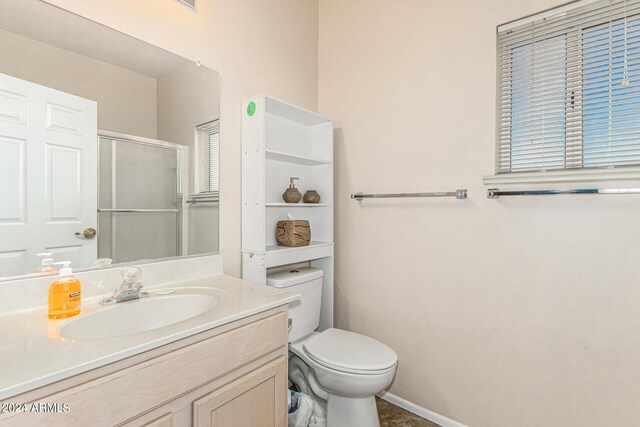 full bath featuring toilet, a stall shower, vanity, and baseboards