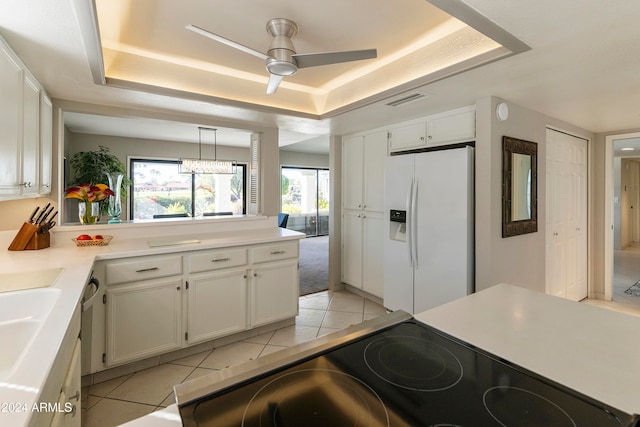 kitchen with white cabinetry, white fridge with ice dispenser, stainless steel range, decorative light fixtures, and a tray ceiling