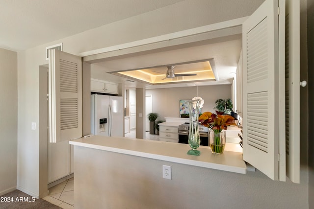 kitchen featuring kitchen peninsula, a tray ceiling, stainless steel electric range oven, white refrigerator with ice dispenser, and white cabinetry