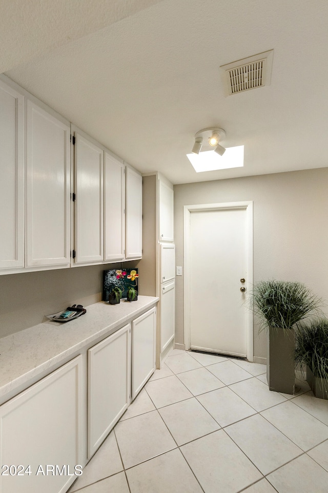 interior space featuring white cabinets and light tile patterned flooring