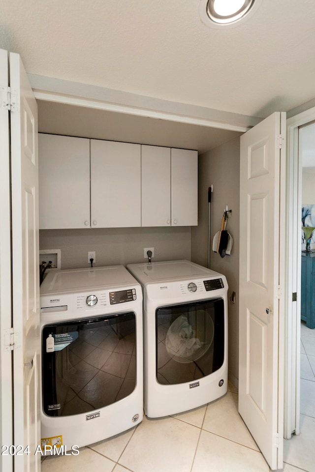 laundry area featuring cabinets, washing machine and dryer, and light tile patterned floors