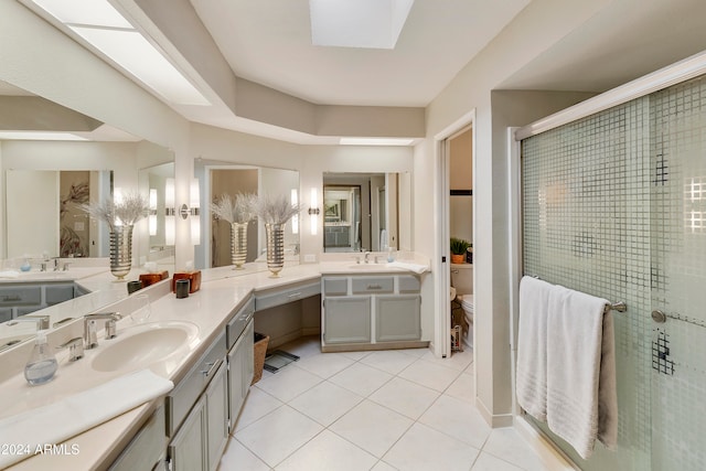 bathroom with a skylight, an enclosed shower, vanity, tile patterned flooring, and toilet