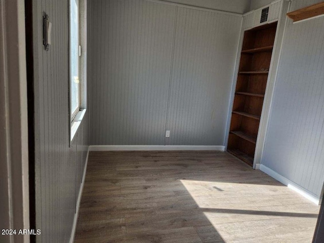 empty room with built in shelves and wood-type flooring