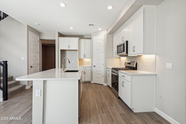 5815 E Covey Ln, Phoenix, AZ 85054 - kitchen featuring stainless steel appliances, a sink, light wood-type flooring, tasteful backsplash, and white cabinets