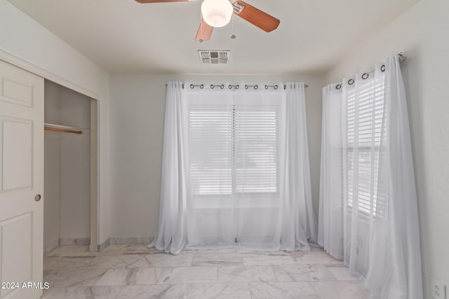 unfurnished bedroom with ceiling fan and a closet