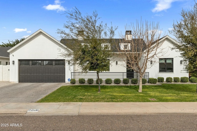 modern farmhouse style home with a chimney, driveway, an attached garage, and a front lawn