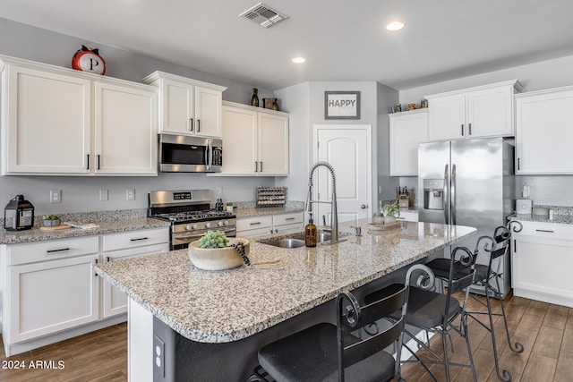 kitchen featuring sink, stainless steel appliances, a kitchen breakfast bar, and an island with sink