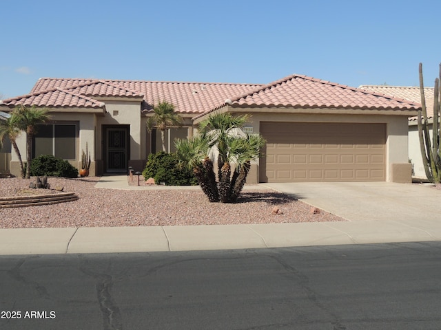 mediterranean / spanish home with a garage, a tiled roof, concrete driveway, and stucco siding