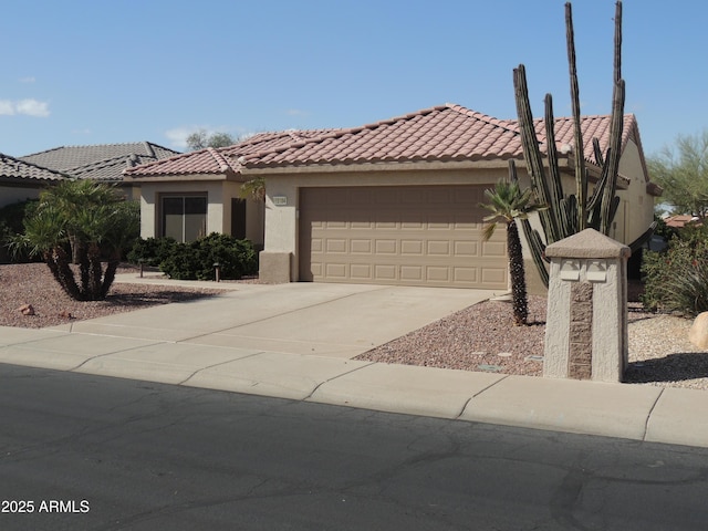 mediterranean / spanish-style house with concrete driveway, a tiled roof, an attached garage, and stucco siding