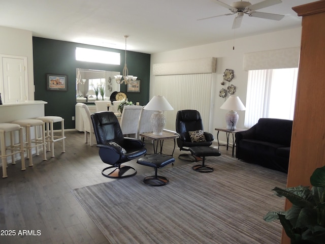 living area featuring ceiling fan with notable chandelier and wood finished floors