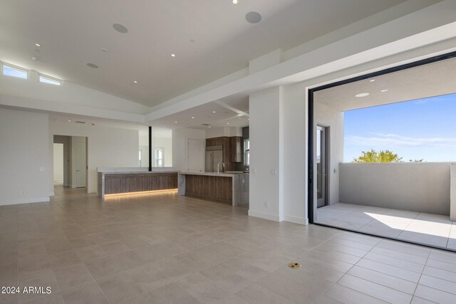 unfurnished living room with light tile patterned floors, high vaulted ceiling, and a wealth of natural light