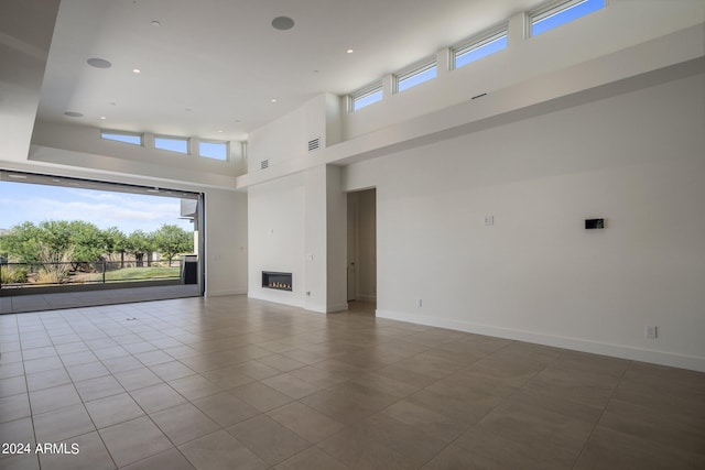 unfurnished living room featuring tile patterned flooring and a high ceiling