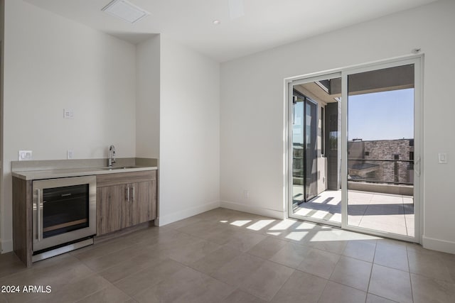 bar featuring light tile patterned floors, beverage cooler, and sink