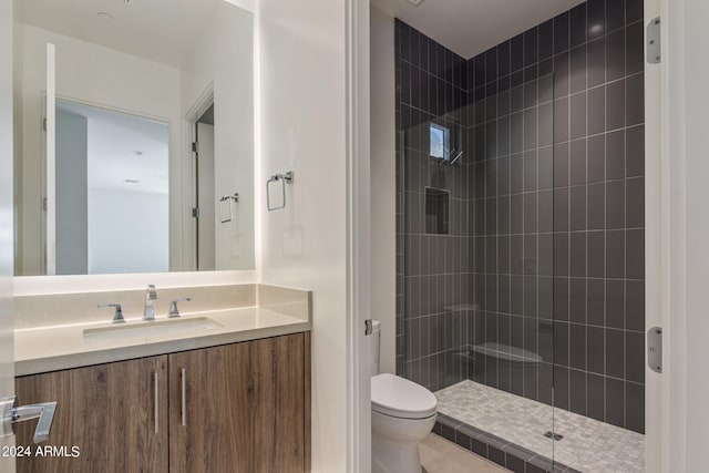 bathroom with tile patterned flooring, a tile shower, vanity, and toilet